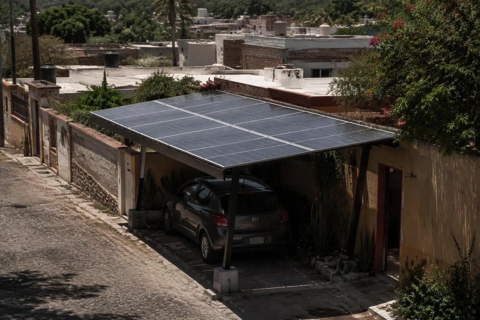 Módulos solares montados sobre la cochera de una casa, con un automóvil estacionado a la sombra